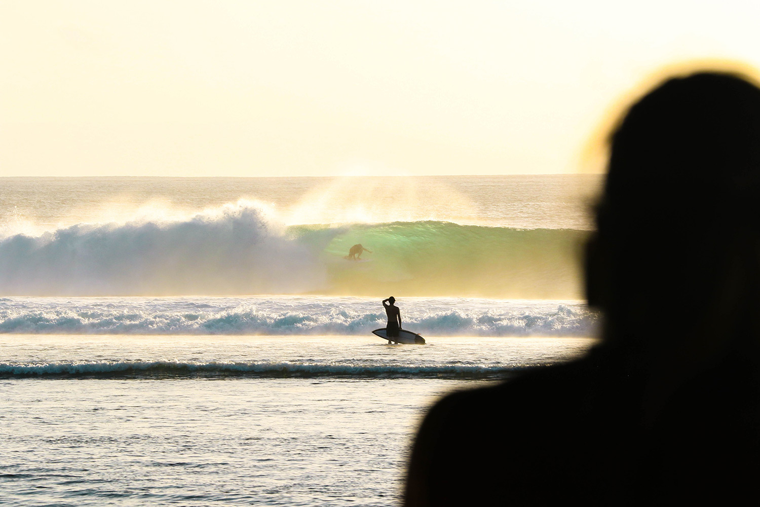 person staring at surfer in the distance in the ocean